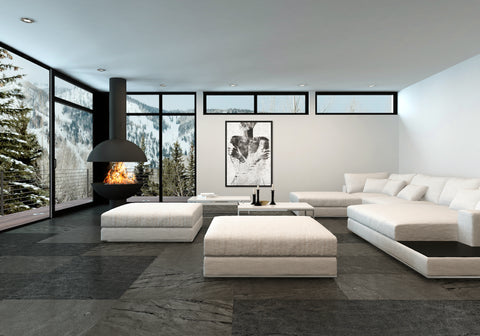 Druck auf schwarzem Metall, Armored Invert von der afrikanischen Künstlerin Linnea Frank in einem Wohnzimmer mit großer Sofalandschaft, auf dem Kunstwerk ist schemenhaft eine Frau zu sehen, die ihre Arme vor dem Körper überkreuzt und ihre Hände an ihren Oberarmen abgelegt hat