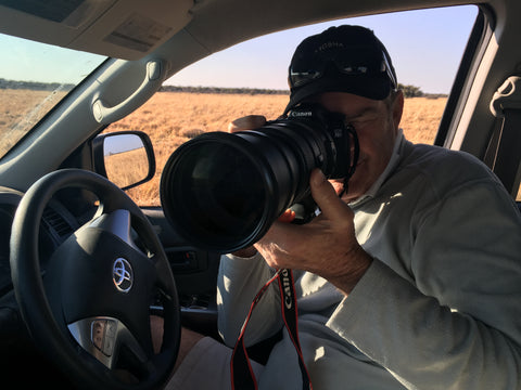 Auf dem Foto sieht man den südafrikanischen Fotografen Nigel Whitehead. Er sitzt in einem Auto und richtet seine Kamera aus dem Fenster